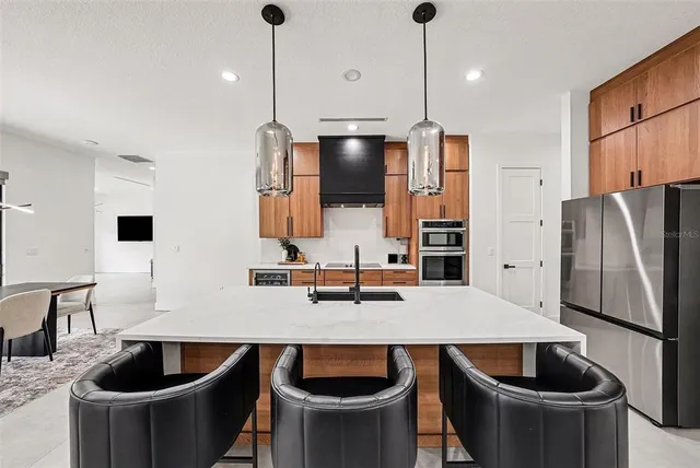 a kitchen with kitchen island a refrigerator a stove a sink and chairs
