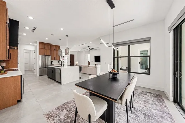 a open kitchen with stainless steel appliances granite countertop a stove a refrigerator a kitchen island a table and chairs