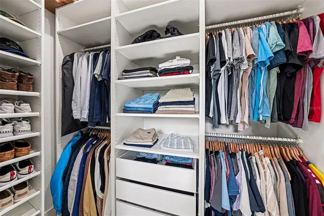 a view of walk in closet with clothes and shoes