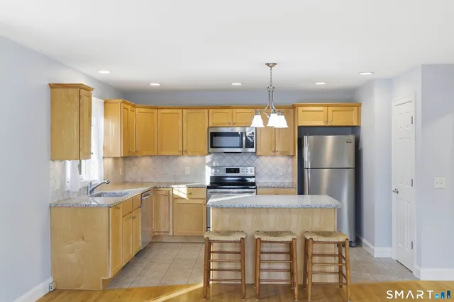 a kitchen with stainless steel appliances granite countertop a stove a sink and a refrigerator