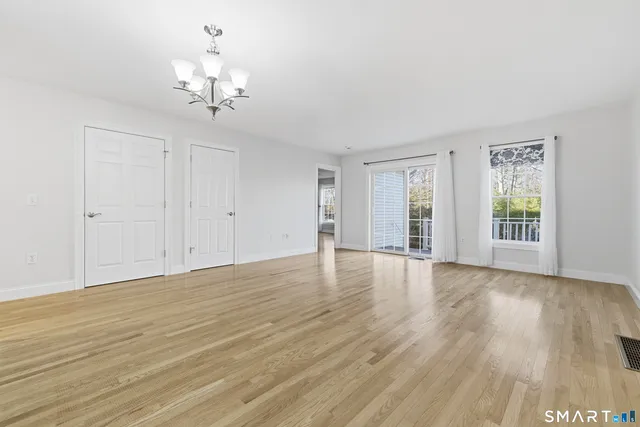 a view of an empty room with wooden floor and window