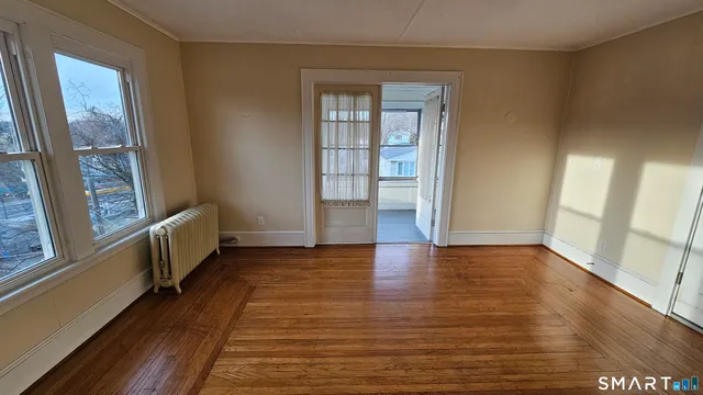 a view of an empty room with wooden floor and a window