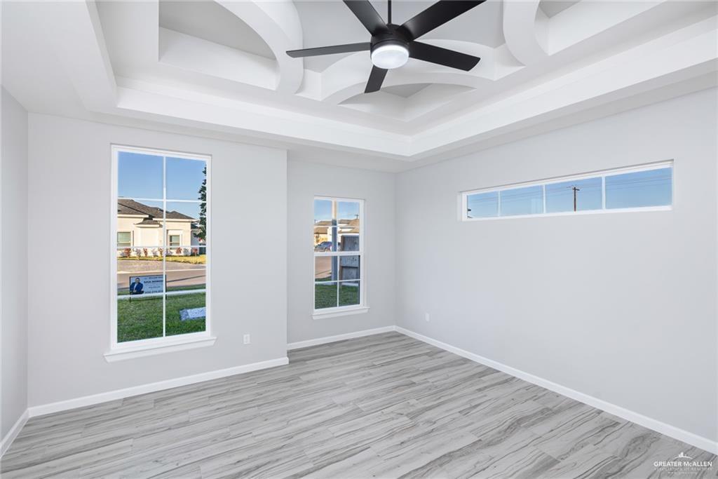 3304 East Rabbit Run Avenue Alton, TX 78573 - Photo 7 of 19 an empty room with wooden floor chandelier fan and windows