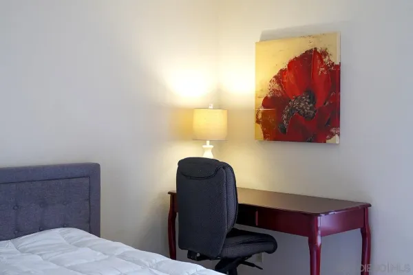 a bedroom with a chair and a lamp on dresser