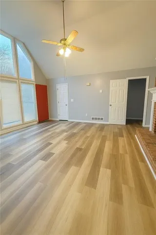 a view of a big room with wooden floor and windows