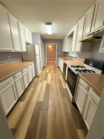 a view of a kitchen with wooden floor and electronic appliances