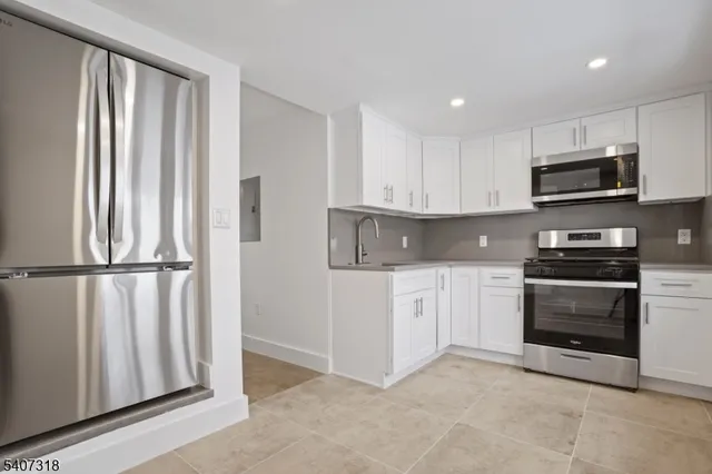 a kitchen with white cabinets and appliances