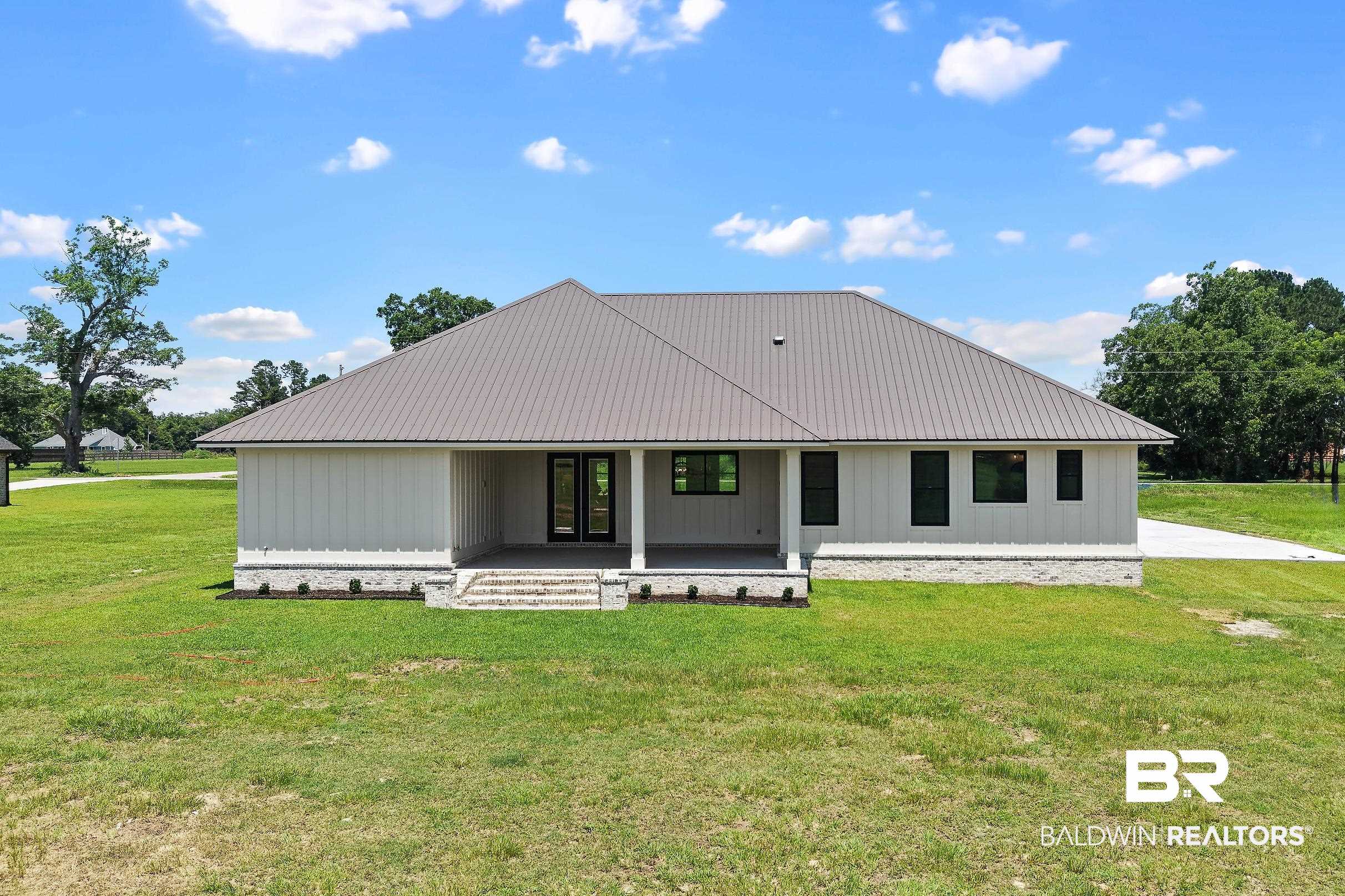 13111 Gopher Court Elberta, AL 36530 - Photo 38 of 41 Contemporary single-story residence featuring a gray metal roof, white vertical siding, and a stone veneer foundation