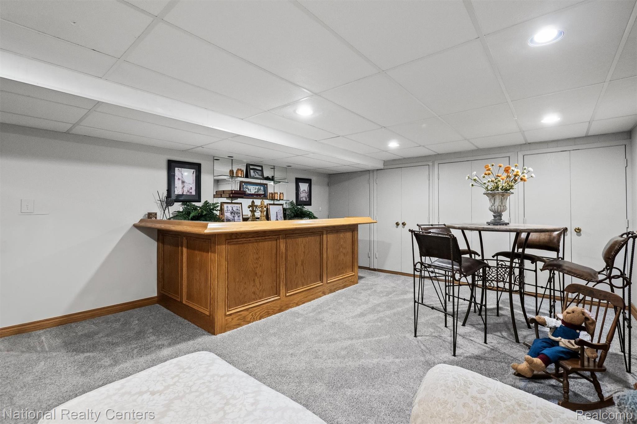 2203 Rochelle Park Drive Rochester, MI 48309 - Photo 33 of 43 Finished basement featuring a built-in wood bar with mirrored shelving, recessed lighting, and light gray carpeting