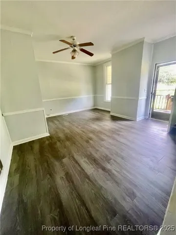 an empty room with wooden floor fan and windows