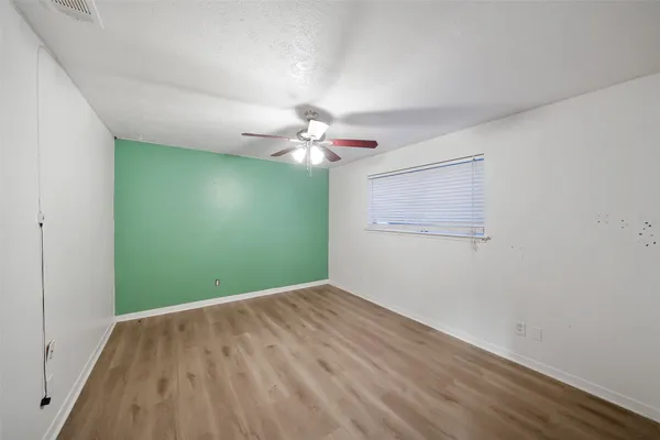a view of a room with a chandelier fan and wooden floor