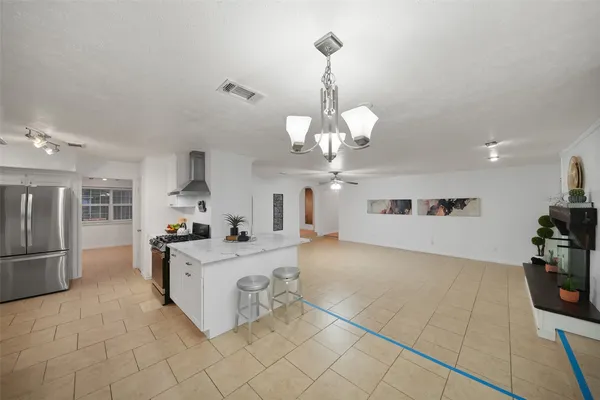 a large kitchen with granite countertop a stove a sink a refrigerator and a chandelier