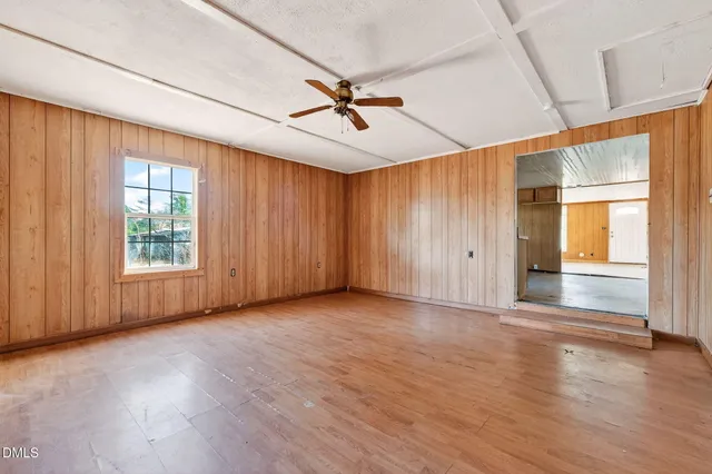 an empty room with wooden floor fan and windows