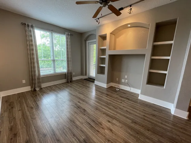 an empty room with wooden floor and windows