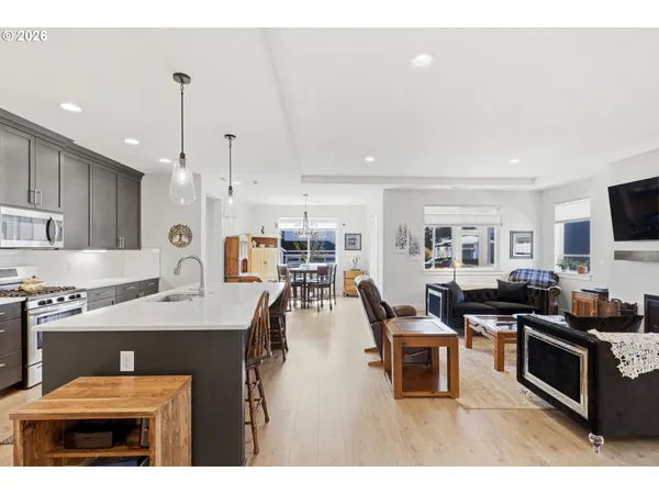 a open kitchen with stainless steel appliances kitchen island granite countertop a stove top oven a sink a dining table and chairs