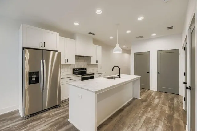 a view of a kitchen with a sink a refrigerator and a stove top oven