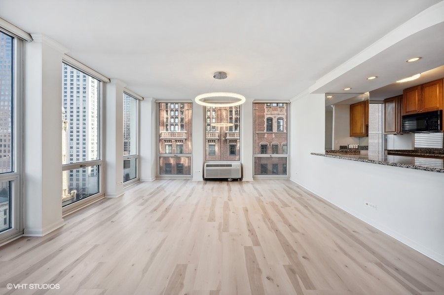 111 East Chestnut Street, Unit 14K Chicago, IL 60611 - Photo 9 of 20 a view of an empty room with a window and wooden floor