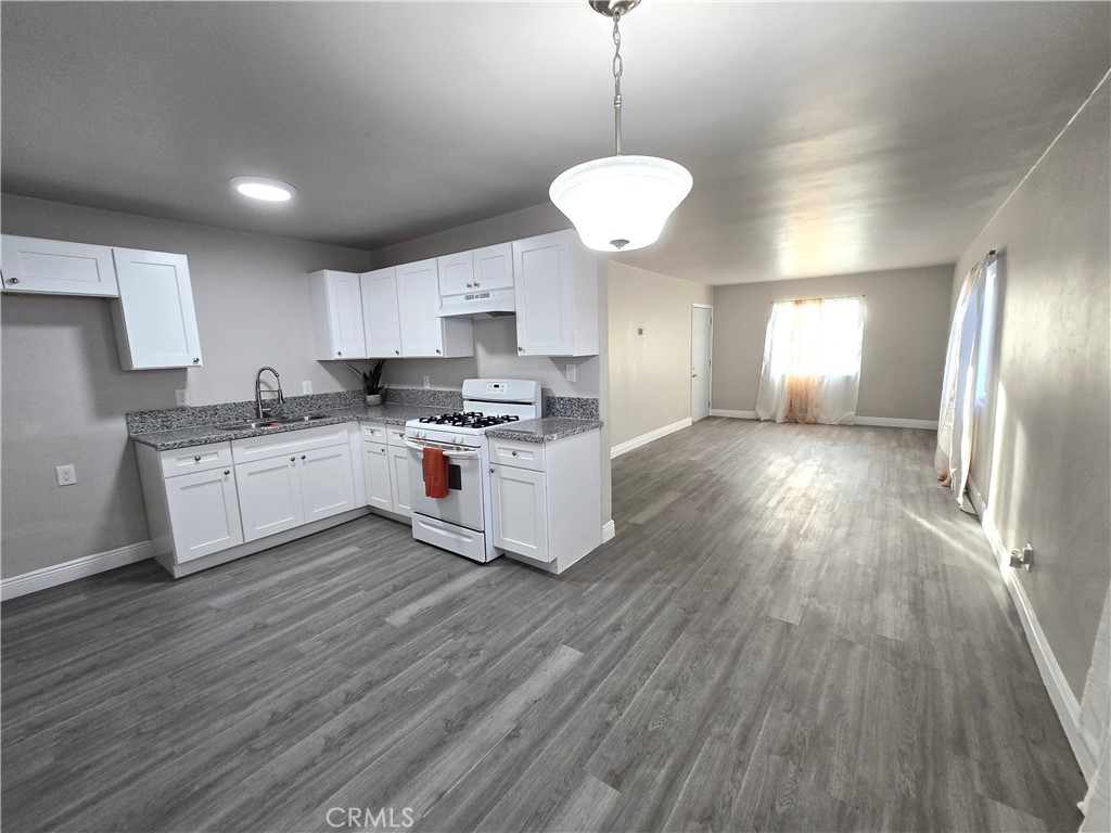 2140 Mahoney Drive Bakersfield, CA 93307 - Photo 11 of 16 a kitchen with stainless steel appliances a stove a sink dishwasher a refrigerator and white cabinets with wooden floor