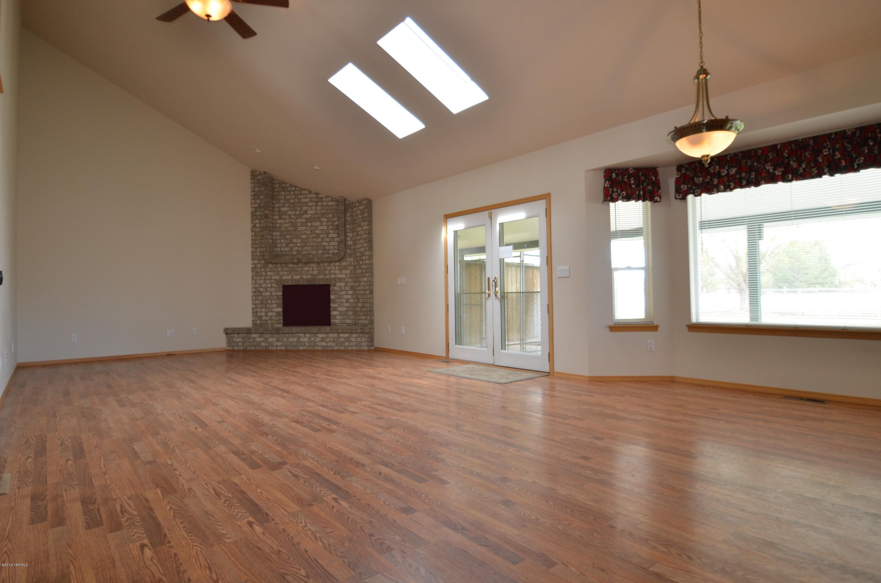 5405 Postma Road Yakima, WA 98901 - Photo 5 of 31 an empty room with wooden floor chandelier fan and windows