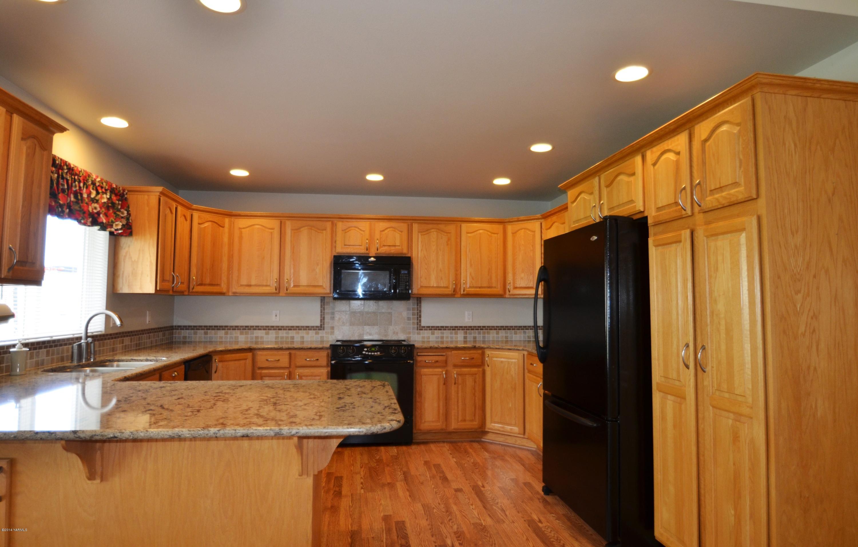 5405 Postma Road Yakima, WA 98901 - Photo 8 of 31 a kitchen with stainless steel appliances granite countertop a refrigerator a sink and a stove with wooden floor