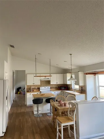 a living room with stainless steel appliances kitchen island granite countertop a table chairs and a view of living room