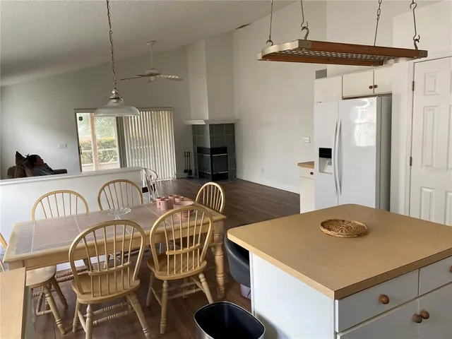a kitchen with stainless steel appliances kitchen island granite countertop a table chairs and a refrigerator