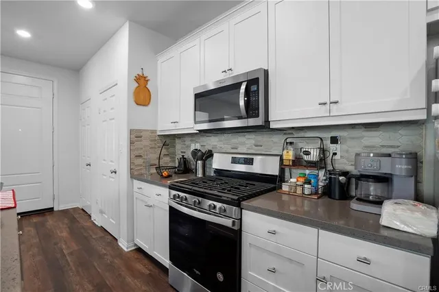 a kitchen with stainless steel appliances granite countertop a stove a sink and a microwave
