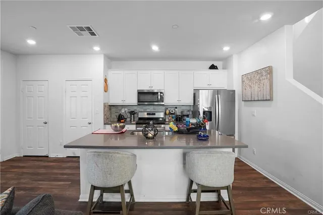 a kitchen with stainless steel appliances granite countertop a dining table chairs refrigerator and sink
