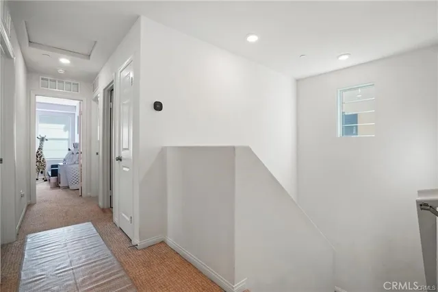a view of a hallway with wooden floor and a bathroom