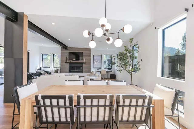 a dining room with wooden floor a chandelier a wooden table and chairs