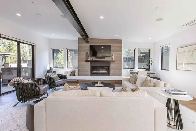 a living room with furniture a flat screen tv and large windows