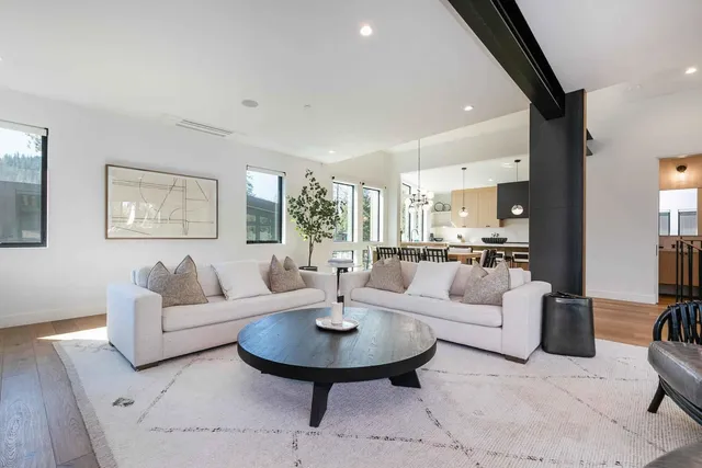 a living room with couches a coffee table and a dining table with wooden floor