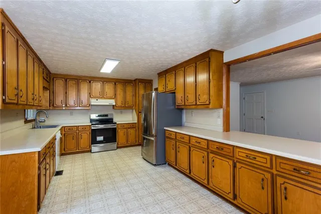 a kitchen with stainless steel appliances granite countertop a stove refrigerator sink and cabinets