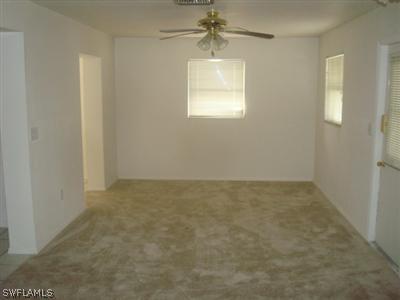 107 Oregon Road West Lehigh Acres, FL 33936 - Photo 6 of 10 an empty room with windows and a chandelier fan
