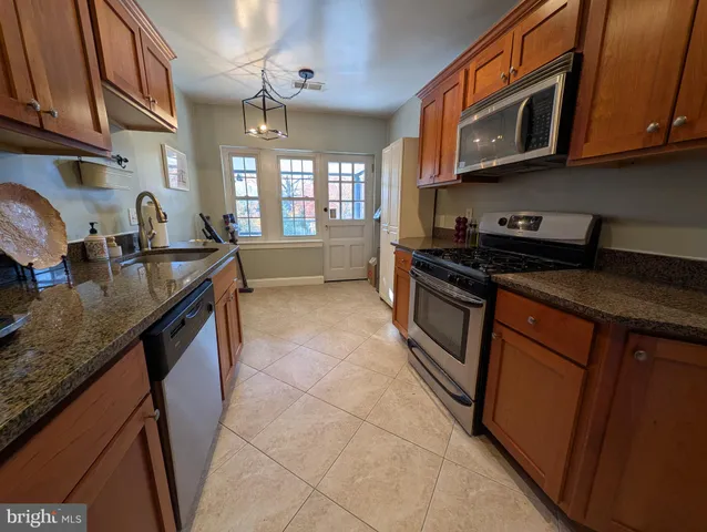 a kitchen with stainless steel appliances granite countertop a stove a sink and a microwave