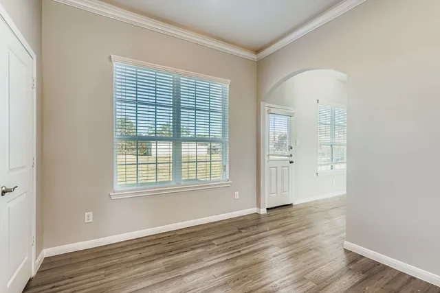 an empty room with wooden floor and windows