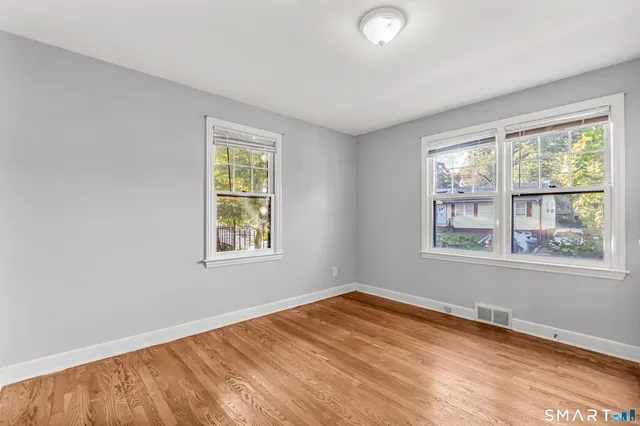 a view of an empty room with wooden floor and a window