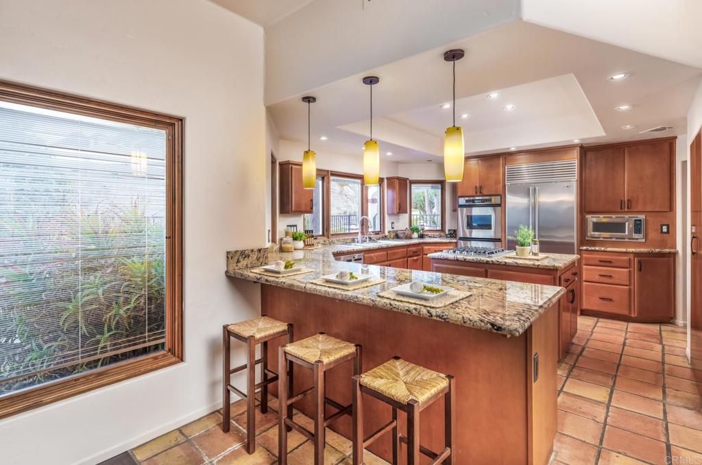 2202 Mountain Vista Drive Encinitas, CA 92024 - Photo 13 of 28 a kitchen with stainless steel appliances granite countertop table chairs sink and cabinets