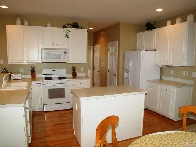 1509 Patterson Grove Road Apex, NC 27502 - Photo 5 of 12 Spacious and bright kitchen is cheerful for everyday tasks. Kitchen is well equipped with gas range, microwave, island, bartop countertop, nice pantry, and tons of cabinetry.