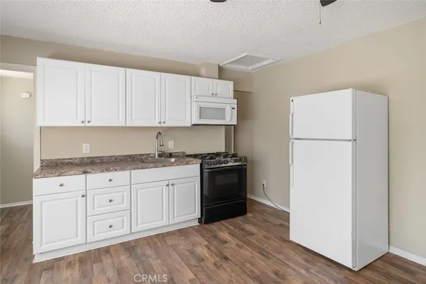 a kitchen with granite countertop white cabinets and refrigerator