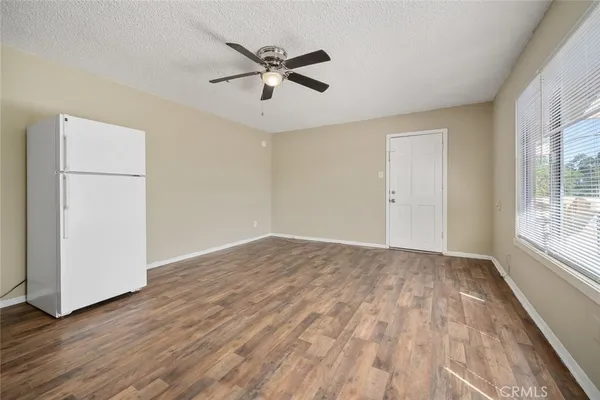 an empty room with wooden floor fan and windows