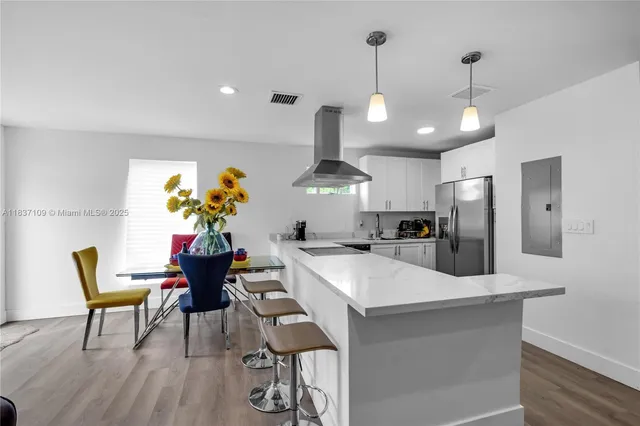 a kitchen with stainless steel appliances kitchen island granite countertop a dining table chairs and white cabinets