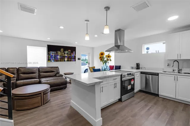 a living room with furniture kitchen view and a wooden floor