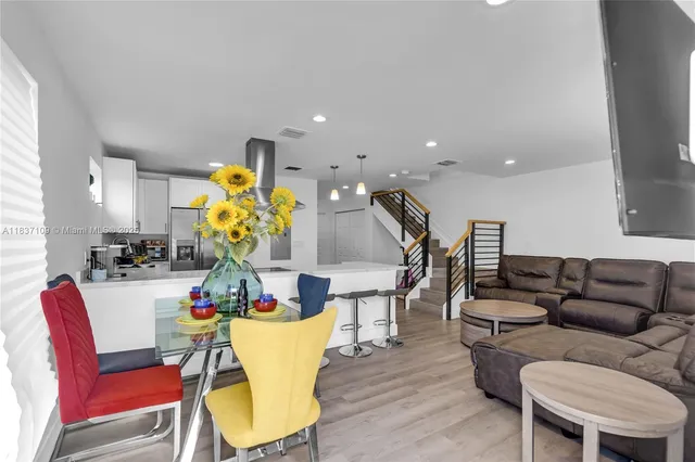 a living room with furniture kitchen view and a chandelier