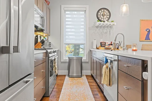 a kitchen with stainless steel appliances granite countertop a refrigerator a stove and a sink with wooden floor