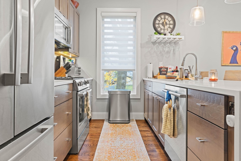 6 Ashland Street, Unit 3 Boston, MA 02122 - Photo 12 of 25 a kitchen with stainless steel appliances granite countertop a refrigerator a stove and a sink with wooden floor