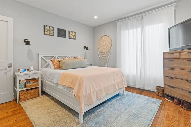 a bedroom with a bed and a flat tv screen on dresser