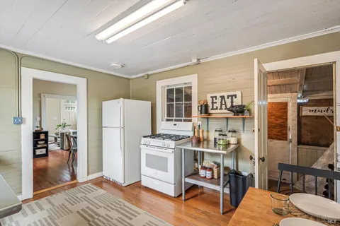 a living room with stainless steel appliances furniture a rug and a refrigerator