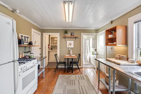 a dining hall with stainless steel appliances granite countertop a stove and a refrigerator a dining table with wooden floor