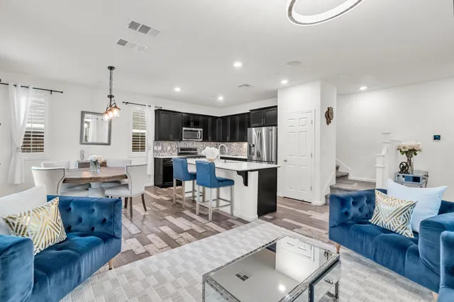 a living room with furniture kitchen view and a chandelier